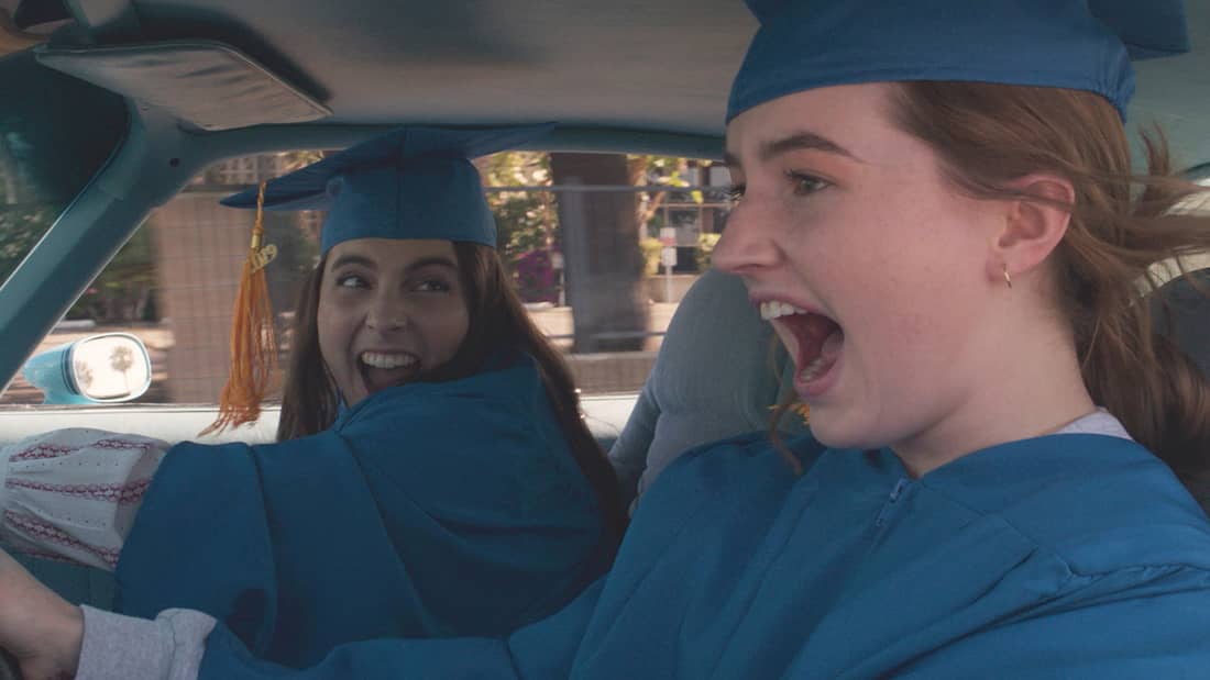 High School girls wearing caps and gowns driving in the car