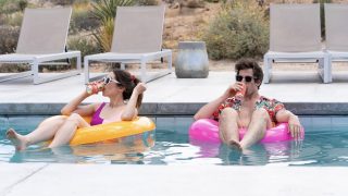 Man and woman sitting on pool floats drinking from cans.