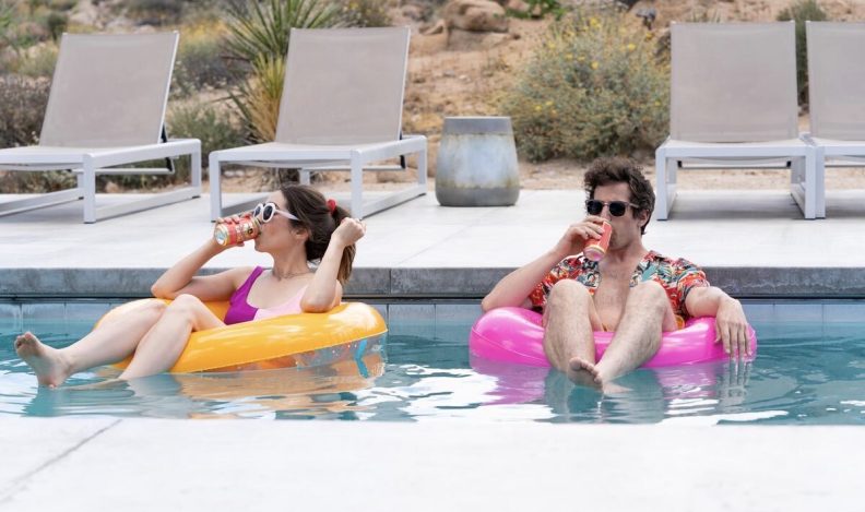 Man and woman sitting on pool floats drinking from cans.